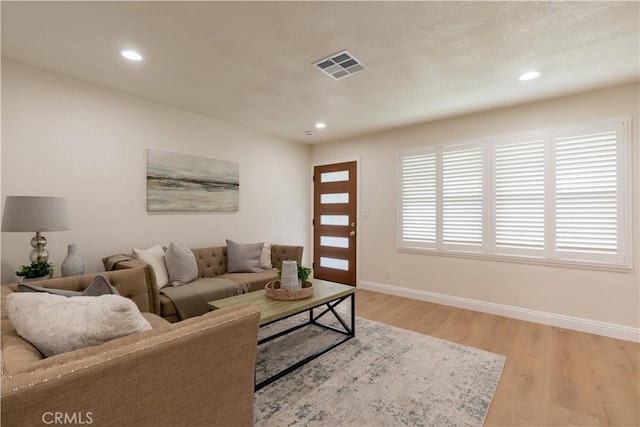 living room with baseboards, light wood-style floors, visible vents, and recessed lighting