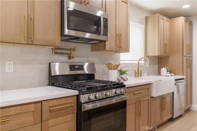 kitchen featuring appliances with stainless steel finishes, tasteful backsplash, a sink, and light stone countertops