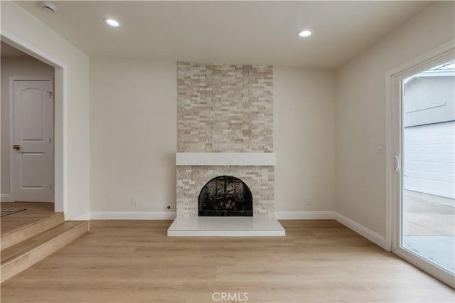 unfurnished living room featuring a fireplace, light wood-style floors, baseboards, and recessed lighting
