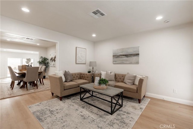 living area featuring baseboards, light wood finished floors, and visible vents