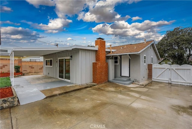 back of property with fence, a patio area, a gate, and board and batten siding