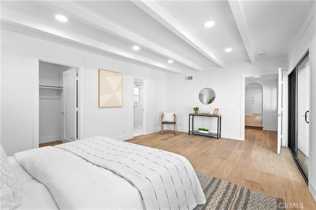 bedroom featuring arched walkways, beamed ceiling, light wood-style flooring, baseboards, and recessed lighting
