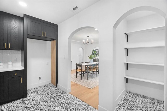 kitchen featuring arched walkways, baseboards, recessed lighting, dark cabinetry, and light countertops