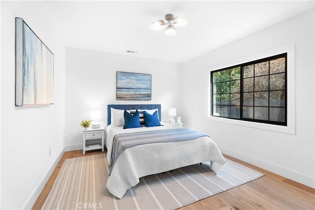 bedroom featuring wood finished floors, visible vents, and baseboards