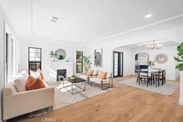living room with a fireplace with flush hearth, arched walkways, a healthy amount of sunlight, and a raised ceiling