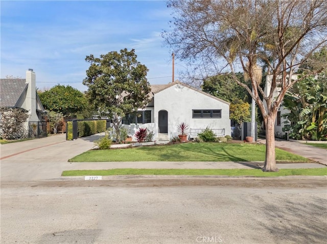 bungalow-style house with driveway, a front yard, and stucco siding