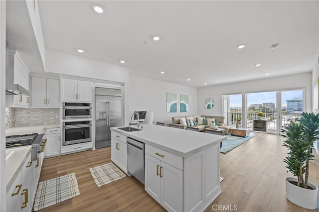 3713 Rivington, Irvine, CA 92612 - kitchen featuring white cabinets, appliances with stainless steel finishes, a sink, light wood-style flooring, and tasteful backsplash