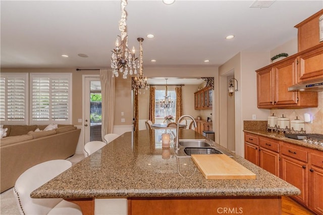 7607 Corona Valley Ave, Eastvale, CA 92880 - kitchen featuring a chandelier, a sink, an island with sink, brown cabinets, and recessed lighting