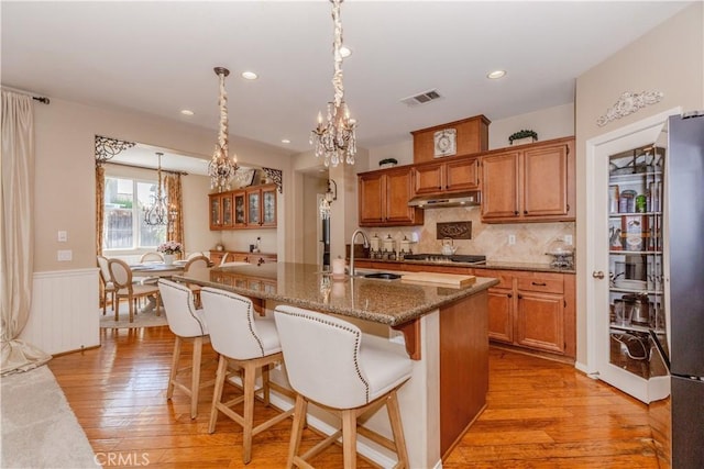 7607 Corona Valley Ave, Eastvale, CA 92880 - kitchen featuring a chandelier, a sink, light wood-style floors, a kitchen breakfast bar, and wainscoting