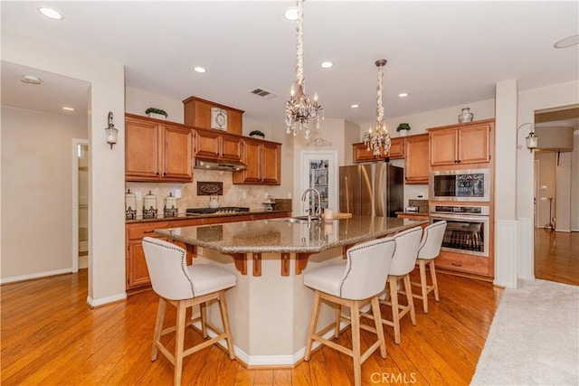 7607 Corona Valley Ave, Eastvale, CA 92880 - kitchen with stainless steel appliances, light wood-style flooring, decorative backsplash, a kitchen bar, and recessed lighting