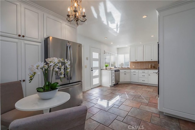 kitchen with a chandelier, stone tile flooring, white cabinetry, backsplash, and appliances with stainless steel finishes