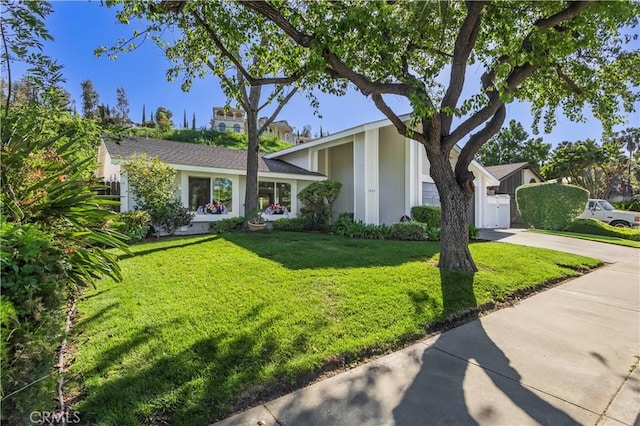 view of front of home with driveway, fence, and a front yard