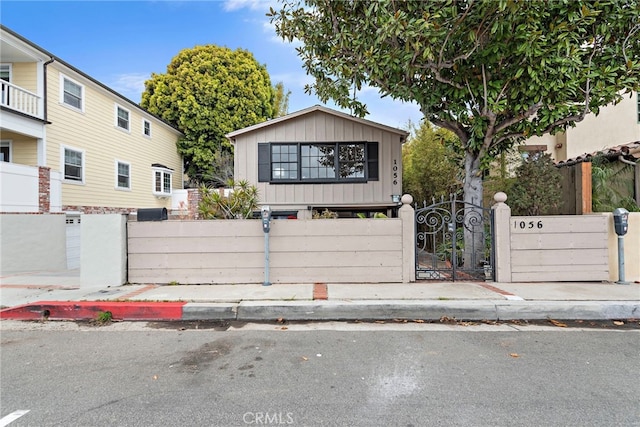 1056 Glenneyre St, Laguna Beach, CA 92651 - view of front facade with board and batten siding, a fenced front yard, and a gate