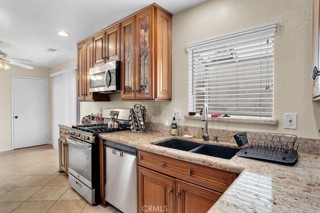 11568 Luanda St, Lakeview Terrace, CA 91342 - kitchen with appliances with stainless steel finishes, a sink, brown cabinets, a ceiling fan, and glass insert cabinets