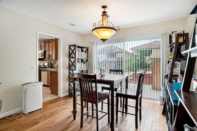 11568 Luanda St, Lakeview Terrace, CA 91342 - dining room with light wood finished floors, a textured ceiling, and baseboards