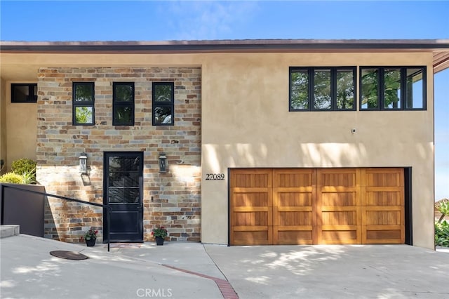 view of front of house with stucco siding, an attached garage, and driveway