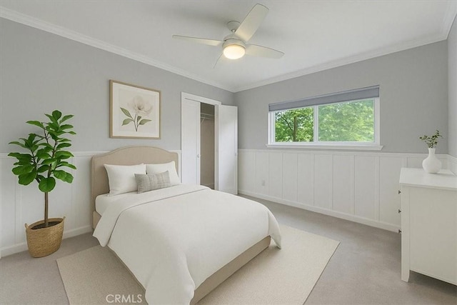 bedroom featuring a closet, ceiling fan, a wainscoted wall, carpet, and ornamental molding