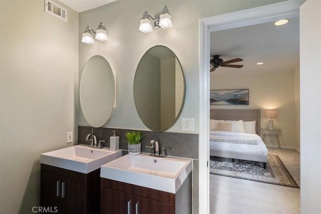 full bath with two vanities, visible vents, ceiling fan, and a sink
