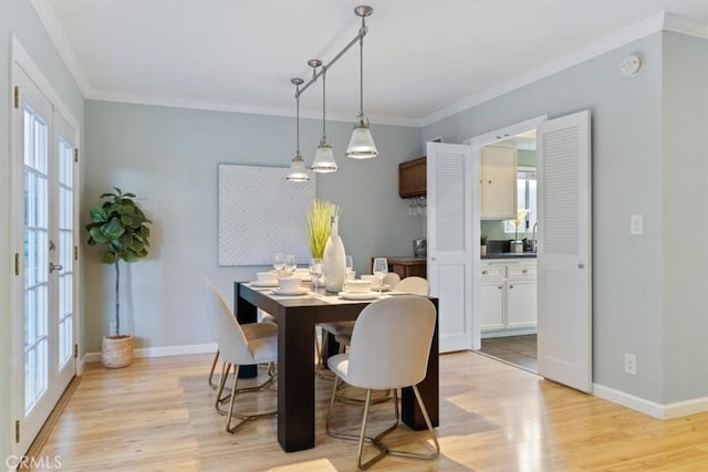 dining room with light wood-style flooring, baseboards, and crown molding