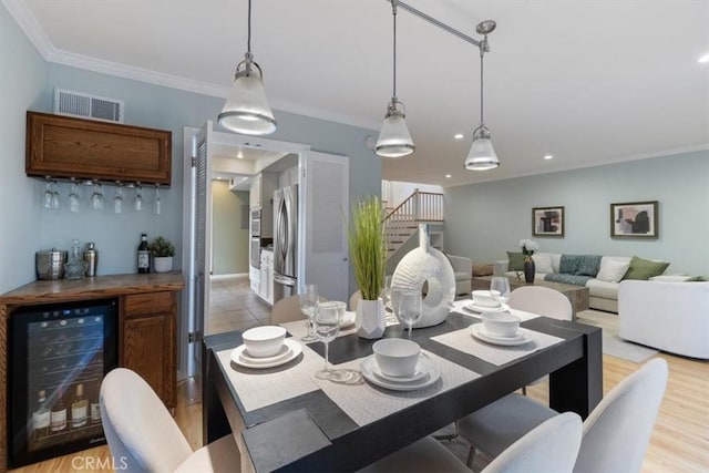dining area featuring crown molding, stairs, beverage cooler, a dry bar, and visible vents