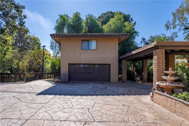 view of home's exterior with concrete driveway, stucco siding, an attached garage, and a tiled roof