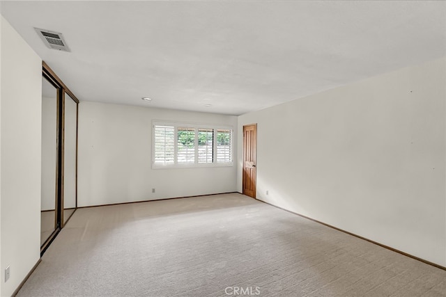 spare room with visible vents, baseboards, and light colored carpet