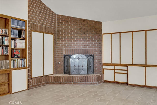 unfurnished living room with a brick fireplace and lofted ceiling