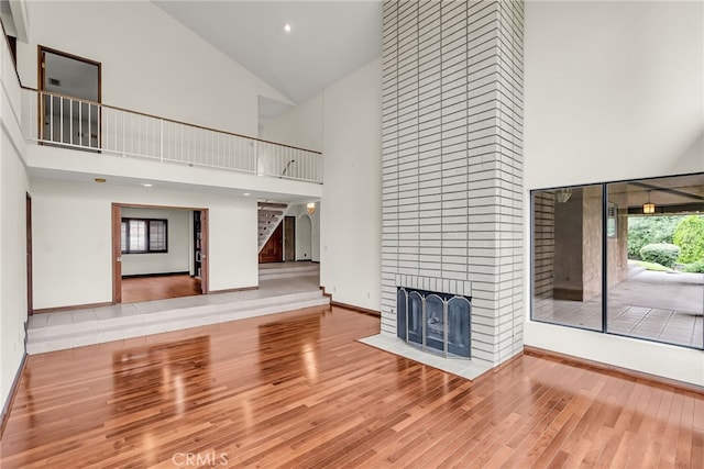 unfurnished living room with baseboards, a high ceiling, a fireplace, and wood finished floors