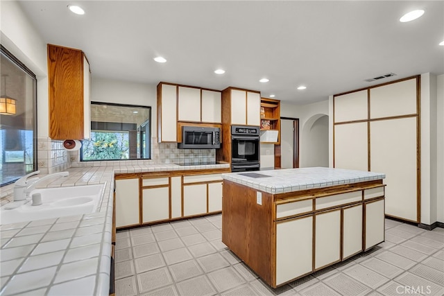 kitchen featuring a sink, stainless steel microwave, tile countertops, and oven