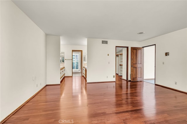 unfurnished room with visible vents, light wood-style flooring, and baseboards