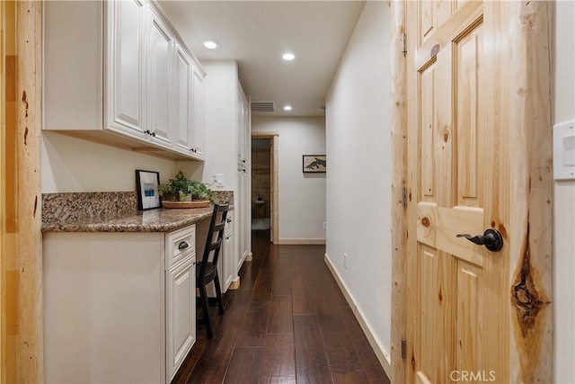 hall featuring dark wood-type flooring, visible vents, baseboards, and recessed lighting