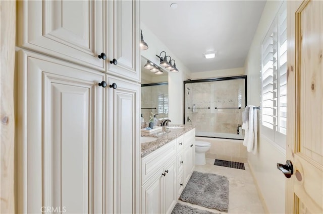 full bathroom featuring a sink, double vanity, toilet, tile patterned flooring, and shower / bath combination with glass door