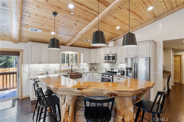 kitchen with a sink, vaulted ceiling with beams, stainless steel appliances, dark wood-style flooring, and visible vents
