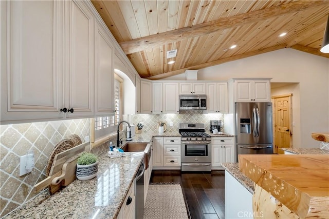 kitchen featuring lofted ceiling with beams, dark wood-style flooring, appliances with stainless steel finishes, and a sink