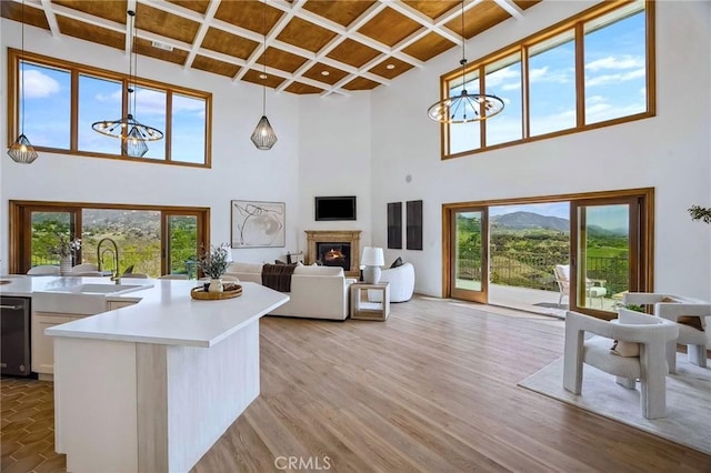 4385 Rainbow Vista Dr, Fallbrook, CA 92028 - living area with a chandelier, coffered ceiling, a towering ceiling, a glass covered fireplace, and light wood-style flooring