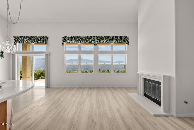 964 Vista Pointe Pl, Santa Paula, CA 93060 - unfurnished living room featuring light wood finished floors, baseboards, and a glass covered fireplace