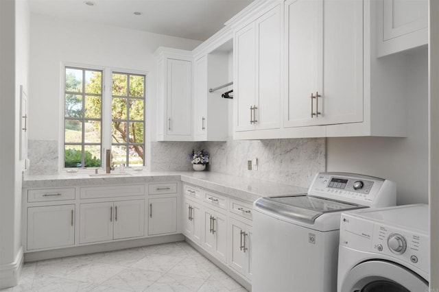 laundry area featuring washing machine and clothes dryer, a wealth of natural light, a sink, marble finish floor, and cabinet space