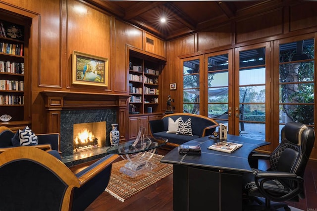 home office featuring dark wood-style floors, a high end fireplace, wooden walls, beamed ceiling, and built in features