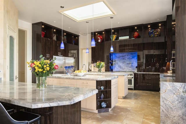 kitchen with light stone counters, a sink, a skylight, a spacious island, and stainless steel built in fridge