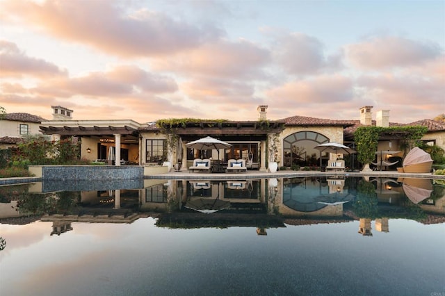 back of property at dusk featuring a patio area, french doors, an outdoor pool, and stucco siding