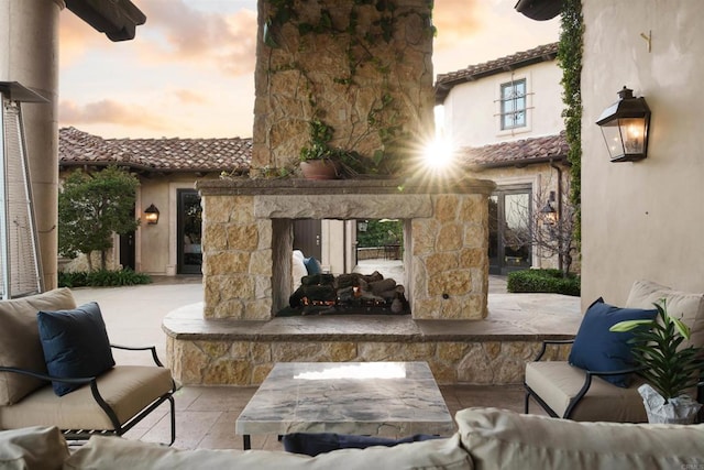 patio terrace at dusk featuring an outdoor living space with a fireplace