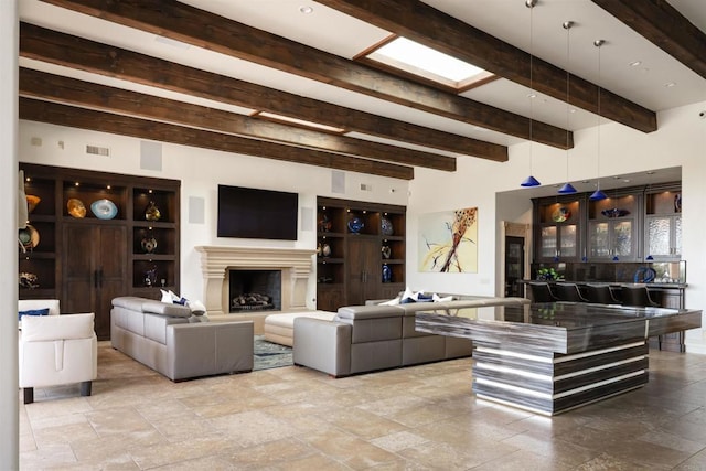 living room with stone tile flooring, beam ceiling, visible vents, and a fireplace