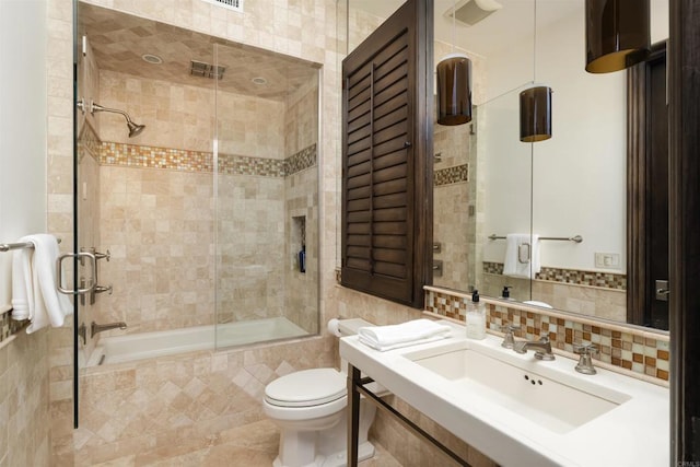 full bath with a sink, toilet, tile walls, backsplash, and tiled shower / bath combo