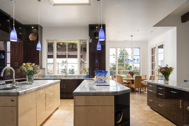 kitchen with a center island, light stone countertops, a sink, and light tile patterned floors