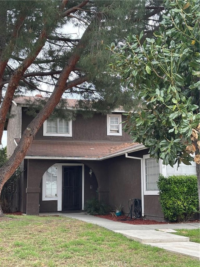 traditional-style home featuring stucco siding and a front lawn