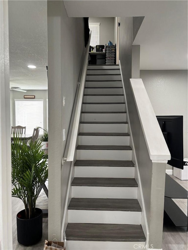 stairway with wood finished floors and a wealth of natural light