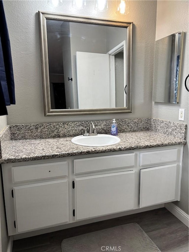 bathroom with a textured wall, vanity, and wood finished floors
