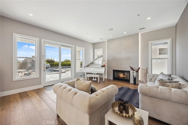 living area featuring recessed lighting, wood finished floors, a fireplace, baseboards, and visible vents