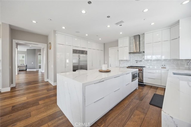 kitchen with high end appliances, modern cabinets, a large island, and wall chimney exhaust hood