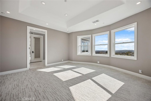 spare room with recessed lighting, a raised ceiling, visible vents, light carpet, and baseboards